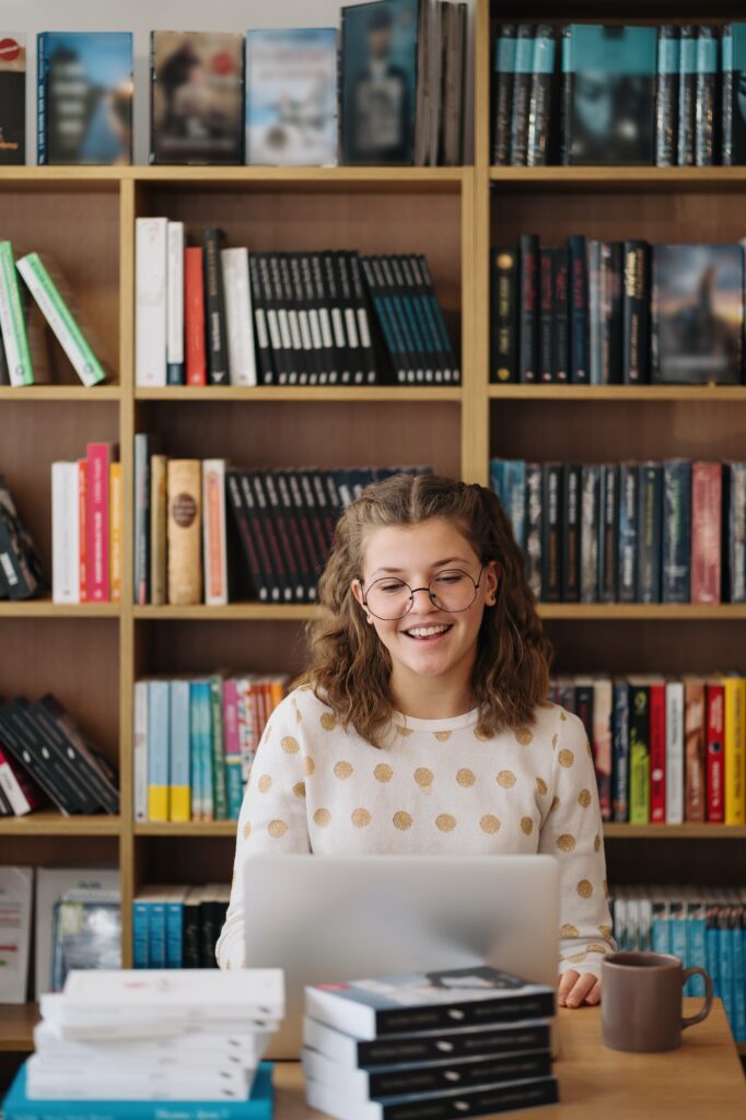 Girl studying among books using laptop