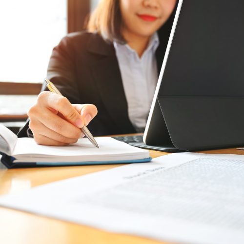 Audit business woman working with notebook and tablet on desk.