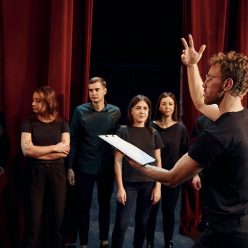 Group of actors in dark colored clothes on rehearsal in the theater