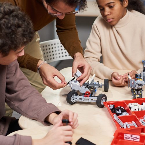 Man teaching children to build the robot