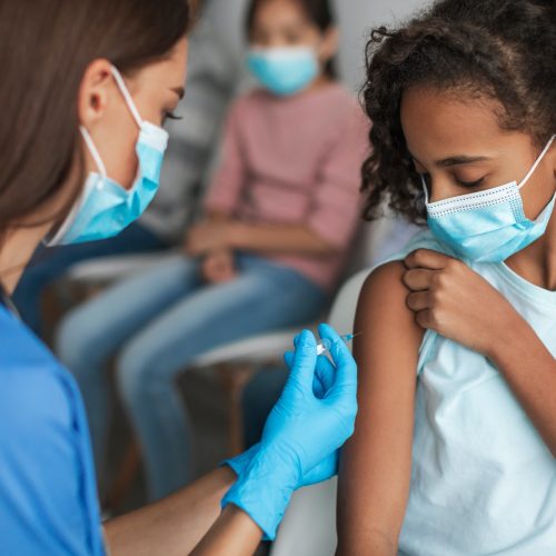 Nurse Vaccinating Black Preteen Girl Injecting Vaccine Against Covid-19 Indoors