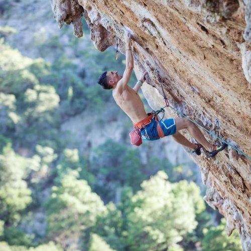 Rock climber on challenging route on overhanging cliff